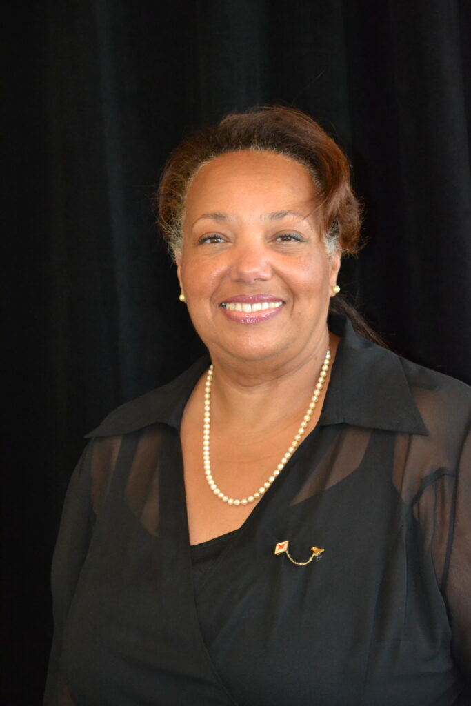 A woman in black shirt and necklace smiling.