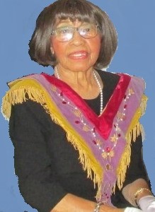 A woman wearing a colorful outfit and pearls.