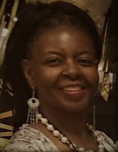 A woman with long earrings and white necklace.