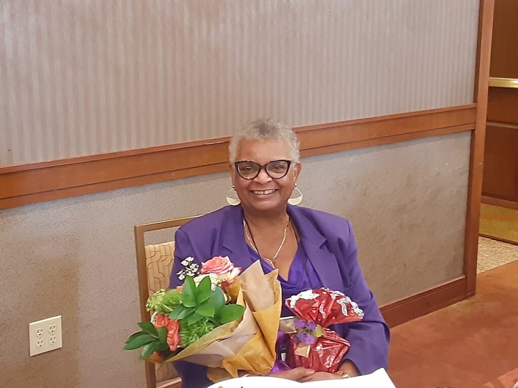 A woman sitting at the table holding flowers.