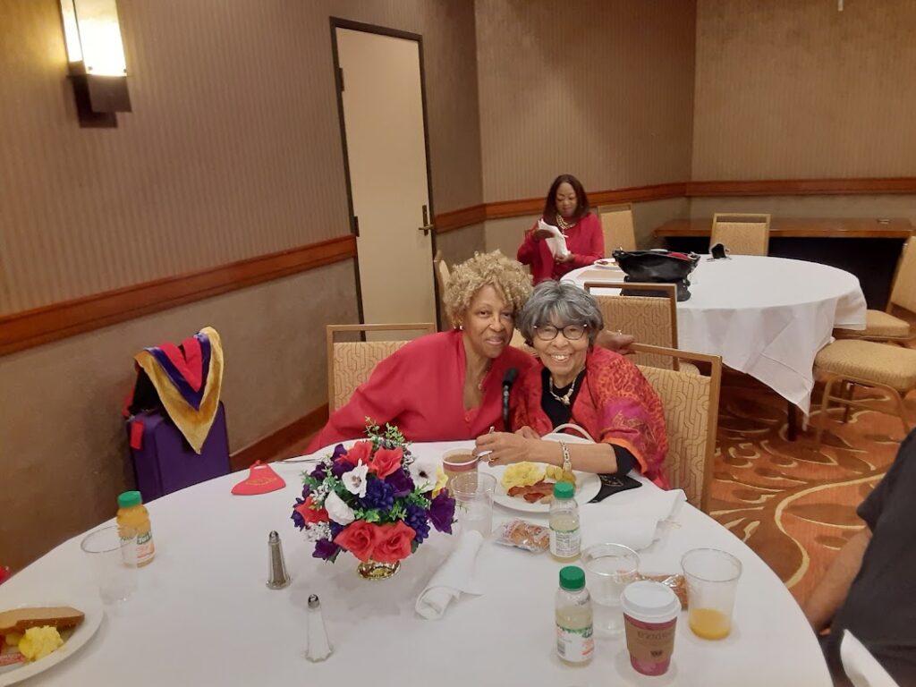 Two women sitting at a table with food.