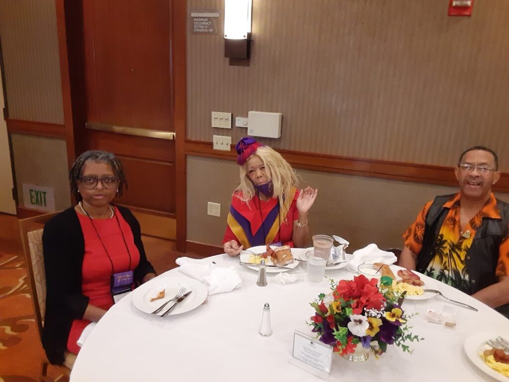 Three women sitting at a table with plates of food.