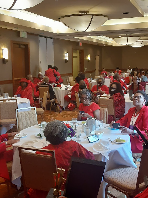 A group of people sitting at tables in red shirts.