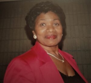 A woman in a red jacket standing next to a wall.