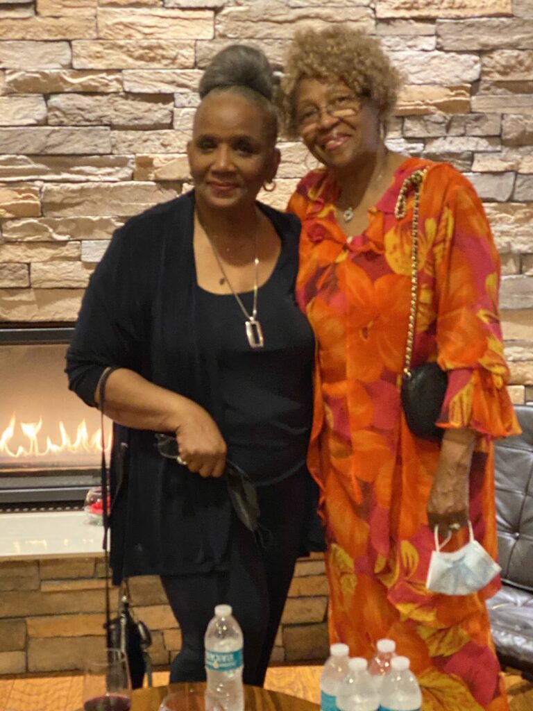 Two women standing next to each other in front of a fireplace.