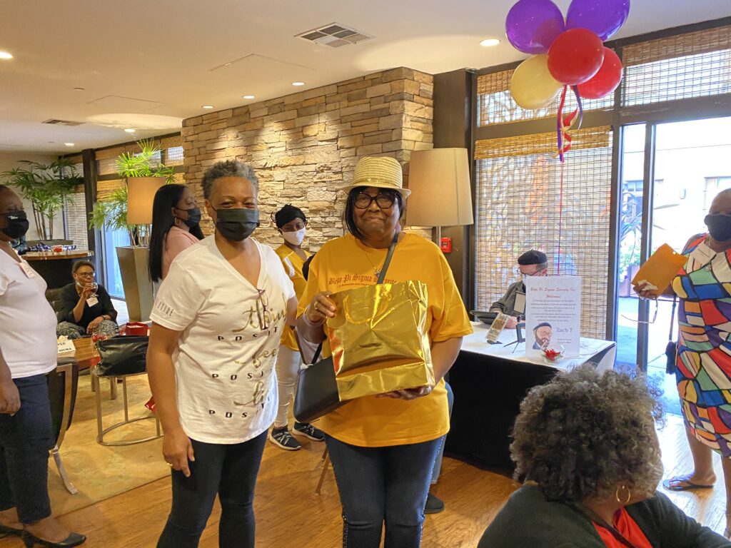 Two women standing in a room with balloons.