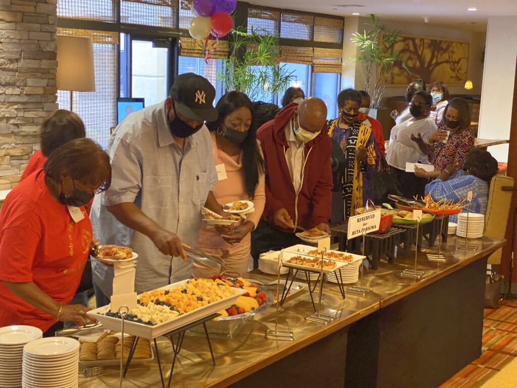 A group of people standing around a buffet line.