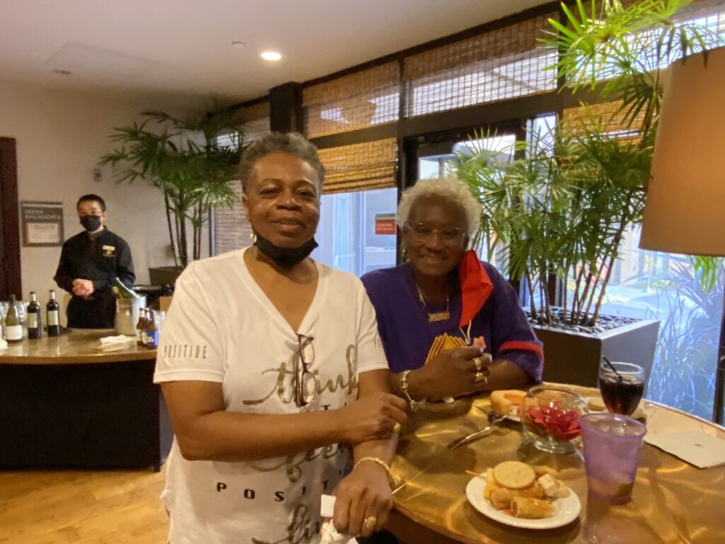 Two women standing at a table with food.