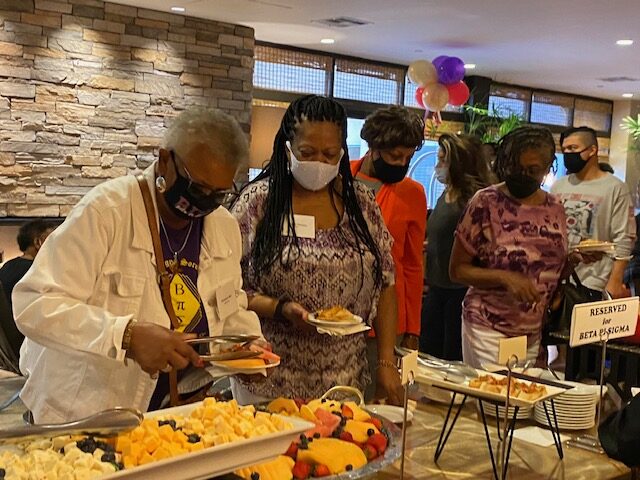 A group of people standing around plates with food.