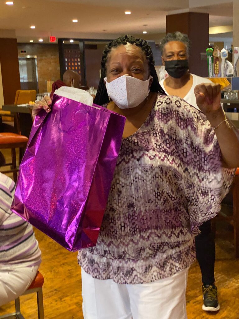 A woman holding up her shopping bag in front of another person.