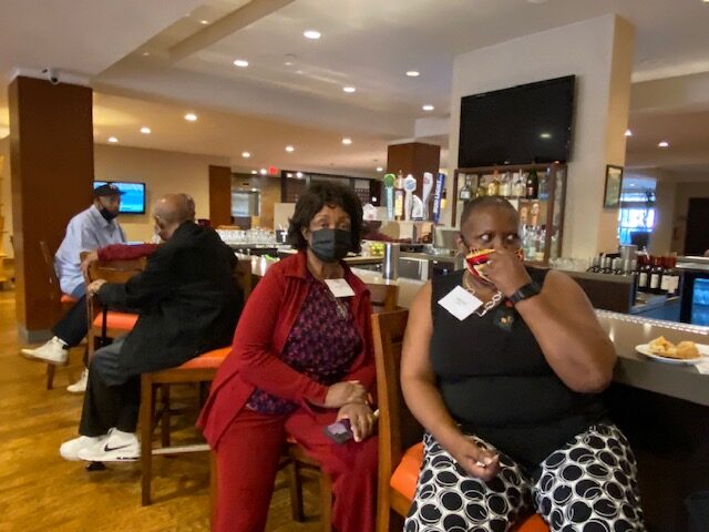 Two women sitting in a restaurant with their faces covered.