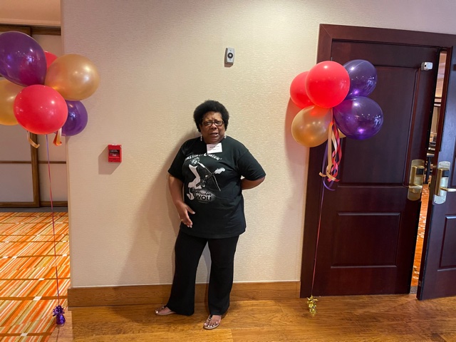 A woman standing in front of balloons and a door.