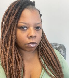 A lady with long brown hairs looking at the camera