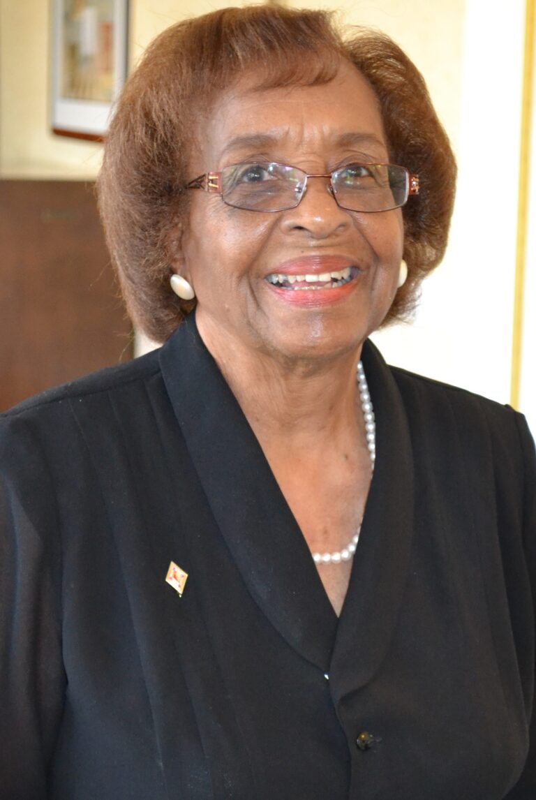 A lady with short brown hairs, smiling at the camera